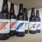 Six 500ml ale bottles arranged on a shelf. Isolation IPA, Lockdown IPA, Oracle Golden Ale, Apocalypse Golden Ale, Mockingbird Stout and Prognosis Brown Ale. Bottle Conditioned real ale brewed in Huntingdon UK