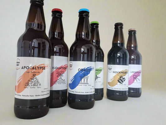 Six 500ml ale bottles arranged on a shelf. Isolation IPA, Lockdown IPA, Oracle Golden Ale, Apocalypse Golden Ale, Mockingbird Stout and Prognosis Brown Ale. Bottle Conditioned real ale brewed in Huntingdon UK