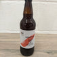 Isolation Smoky IPA in bottle with a red cap. Label shows a desert island with palm tree on a red paint stripe. Isolation smoky IPA, real ale brewed locally in Huntingdon UK